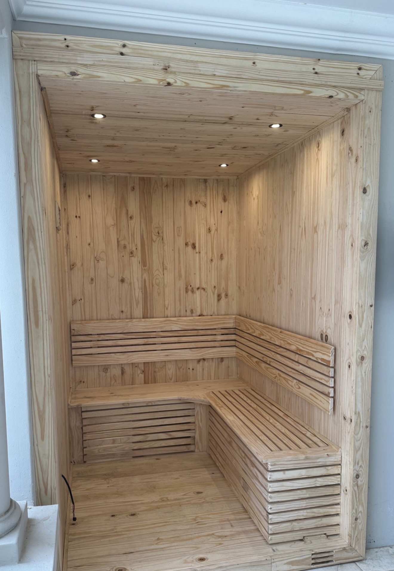 Finished indoor pine sauna with L-shaped bench and recessed lights
