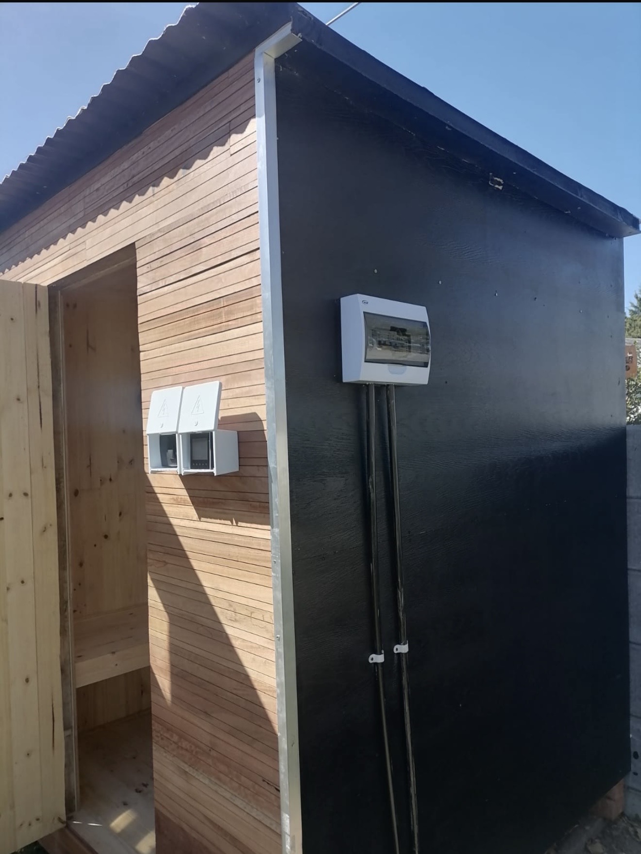 Freestanding outdoor sauna cabin with timber front and black cladding